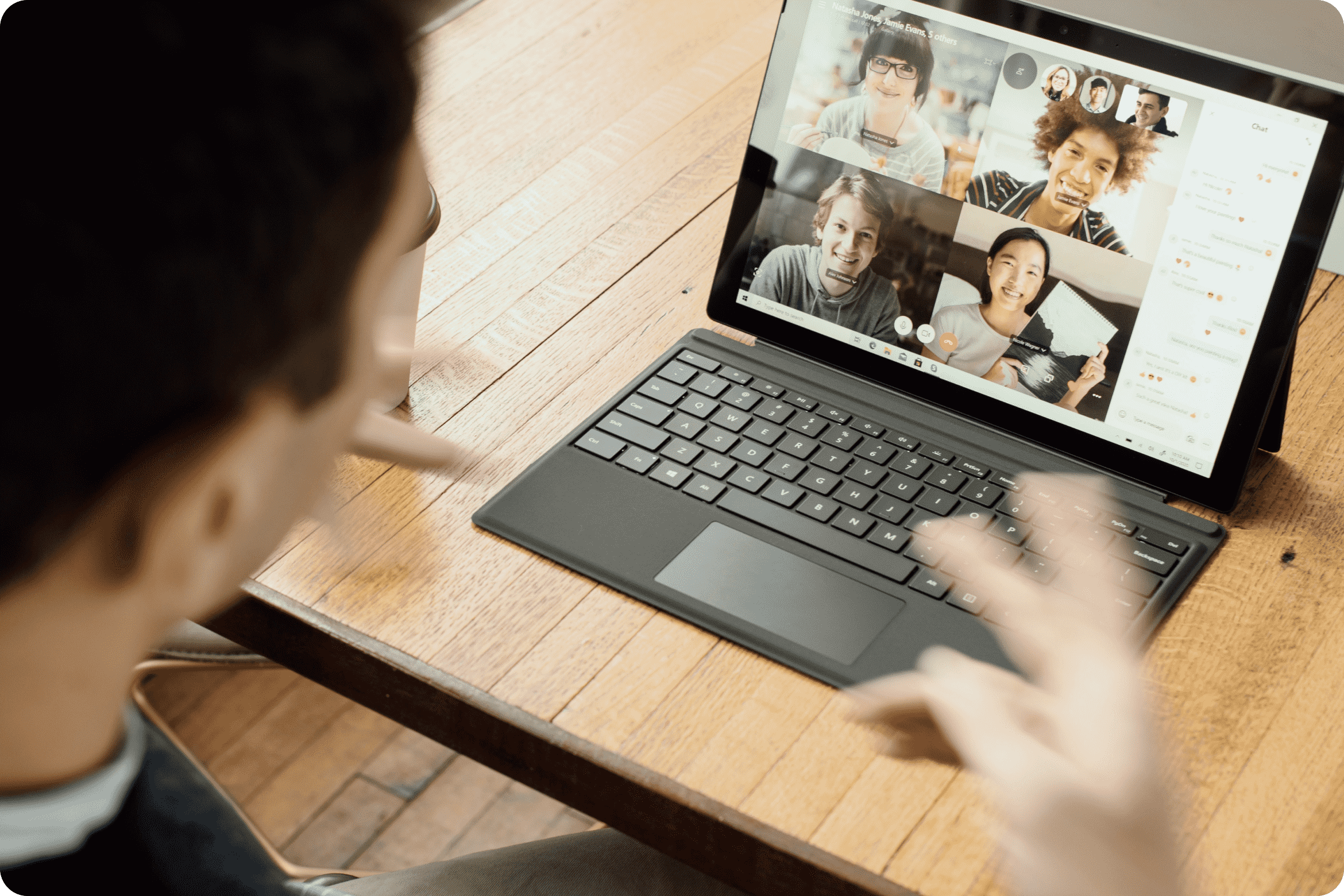 A user collaborates with other smiling faces in a Zoom meeting on a laptop.